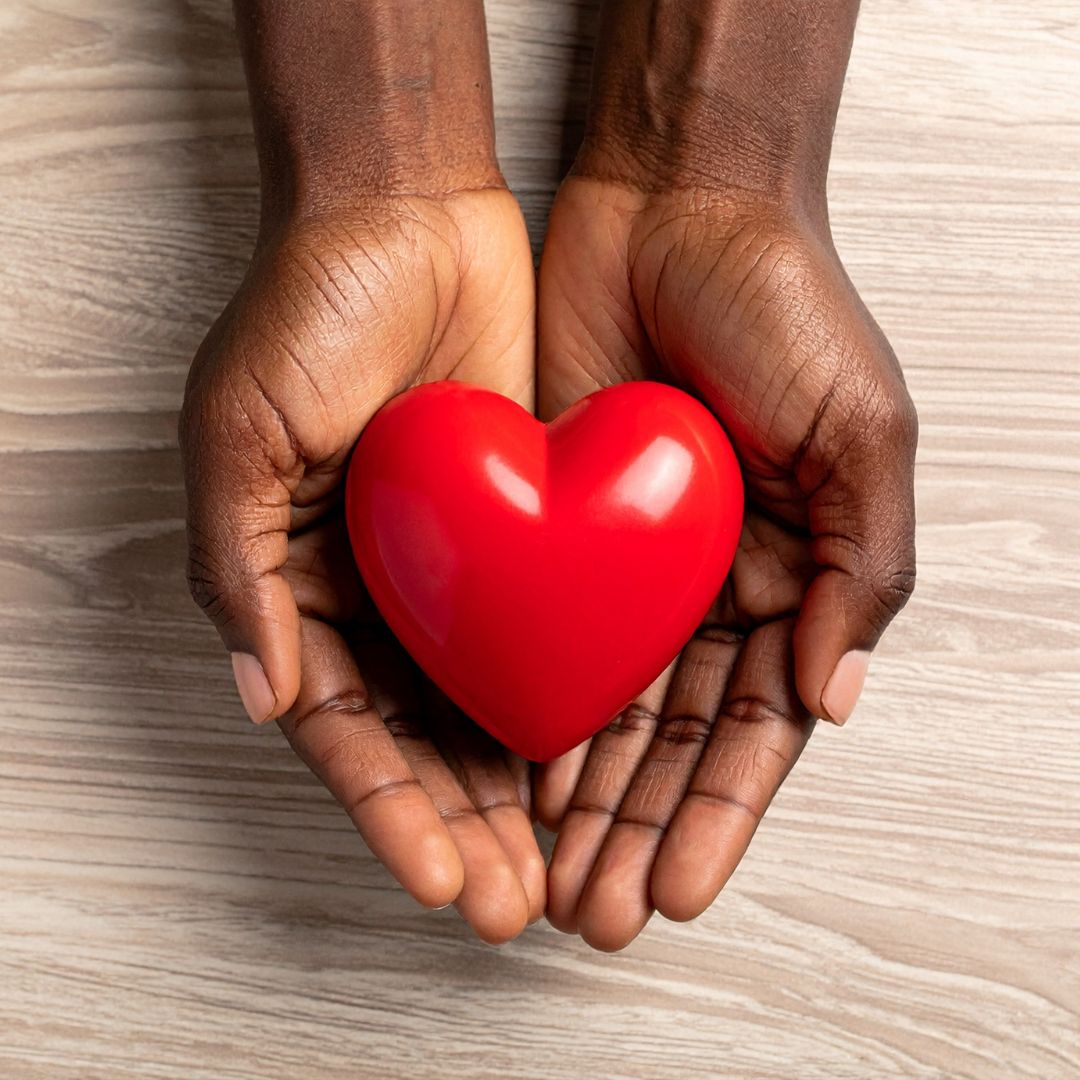 Hands holding a red heart signifying heart health care