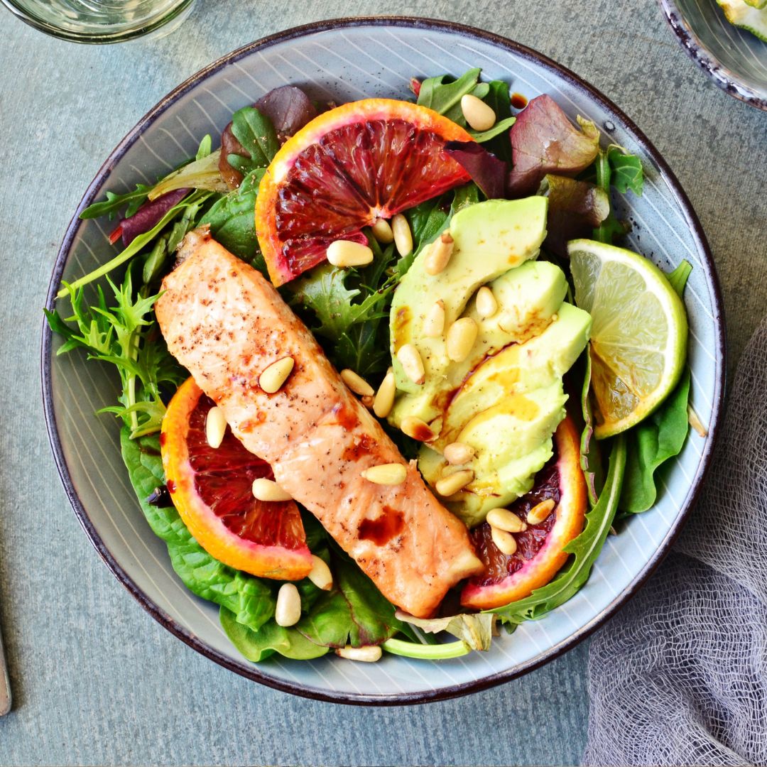 Summer salad with salmon, avocado, seeds and leafy greens for hormone health support